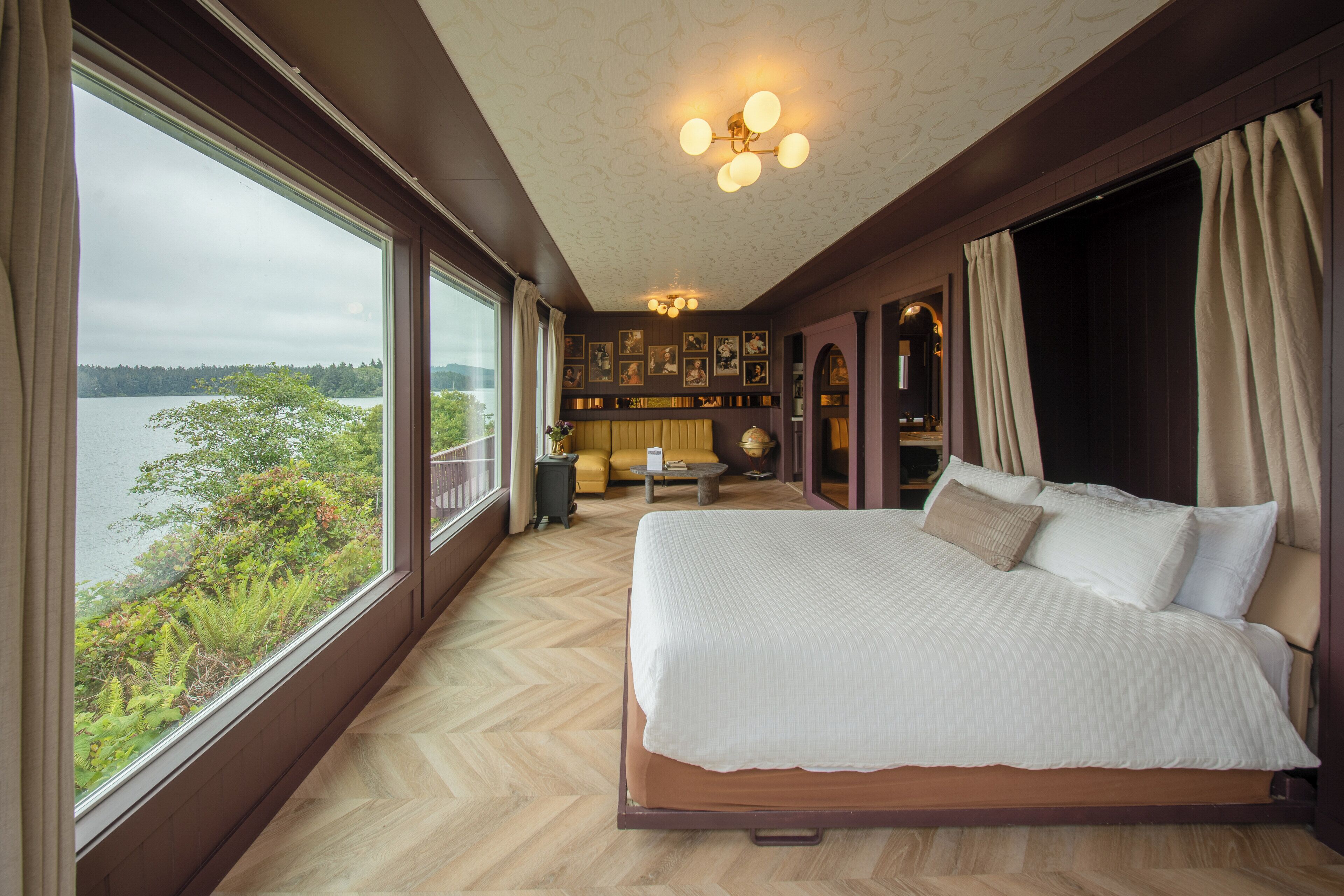 A bedroom with a large bed, a view of a lake, and a ceiling light fixture.