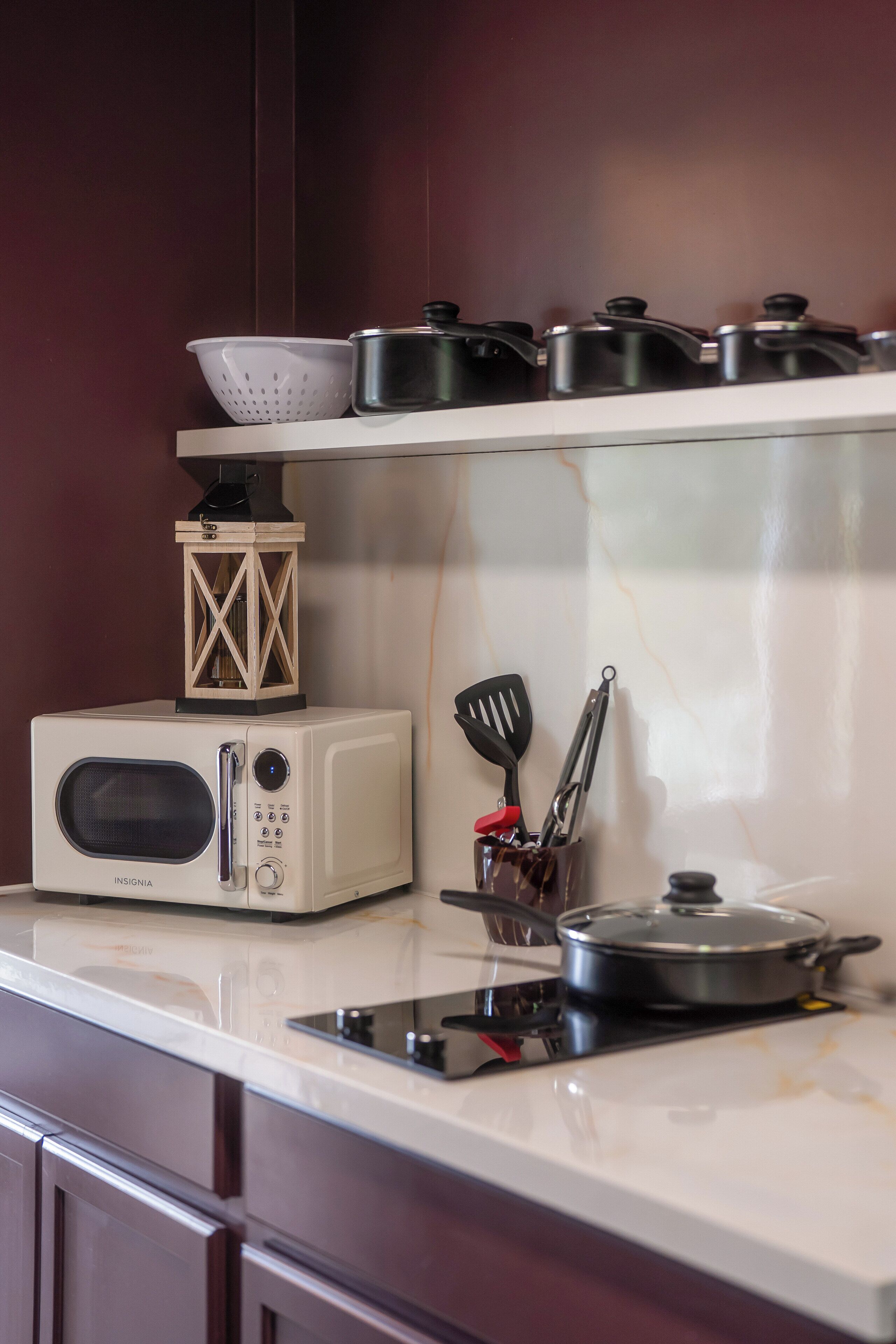 Una cocina con microondas, estufa y una olla sobre la encimera.