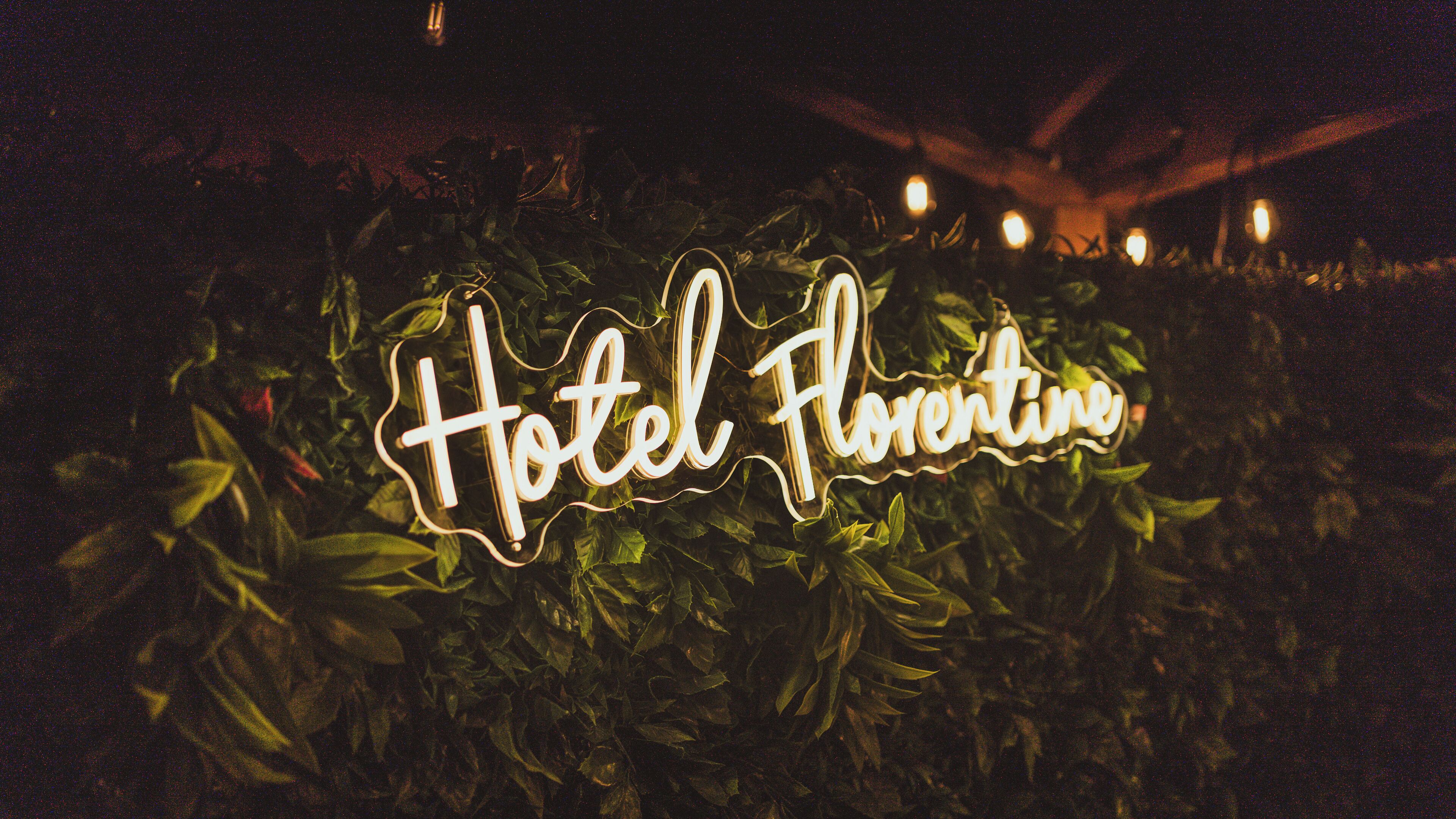 A neon sign reading "Hotel Florentine" amidst greenery.