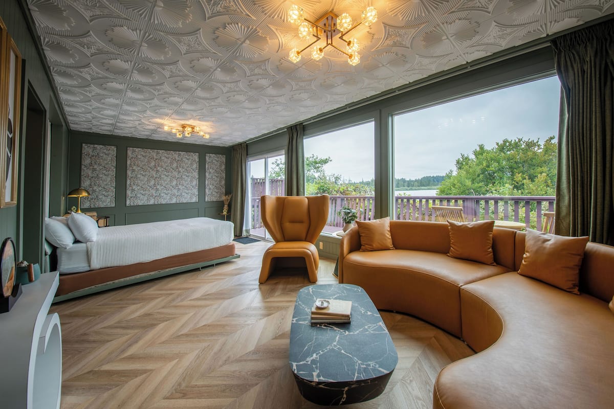 A spacious room with a bed, a sofa, a chair, and a coffee table.