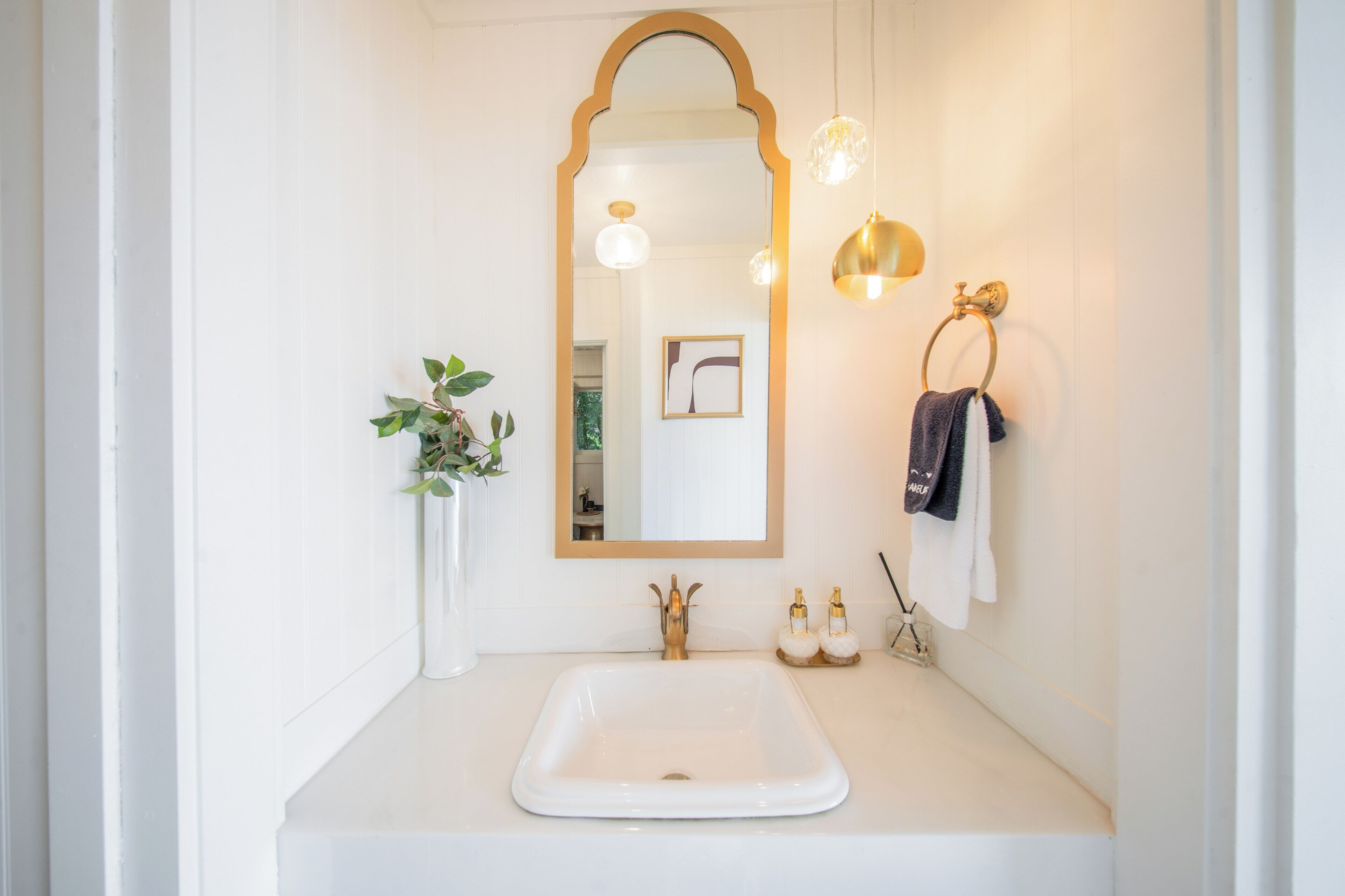 A bathroom with a white sink, a large mirror, and two wall-mounted lights.