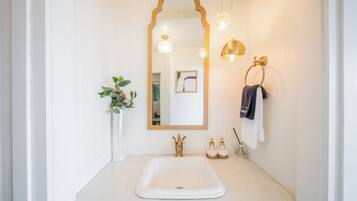 A bathroom with a white sink, a large mirror, and two wall-mounted lights.