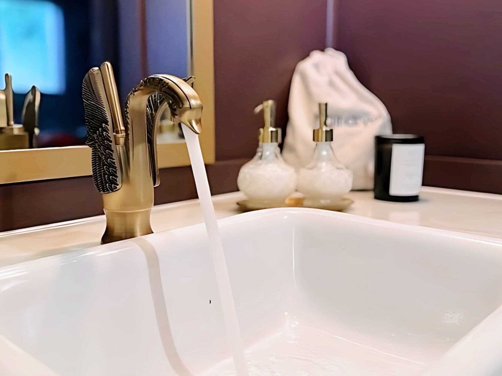 A bathroom sink with a modern faucet, a hand soap dispenser, and a bottle of liquid soap.