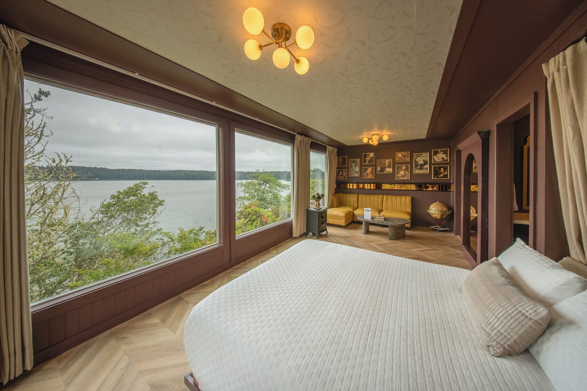 A bedroom with a large bed, a sofa, and a view of a lake.