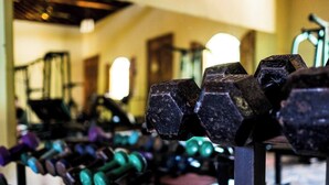 A row of dumbbells in a gym with a mirrored wall and a staircase in the background. - PURE Gym - Spa - Yoga - Lodging (Granada)