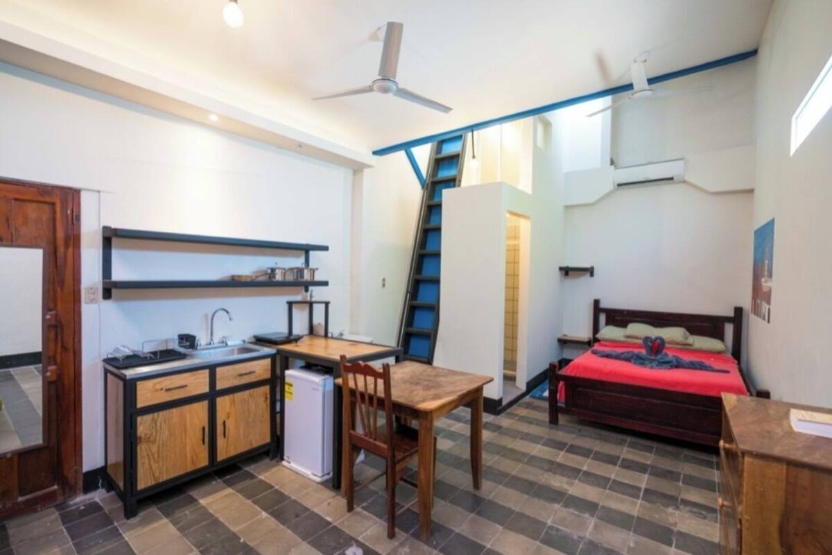 Una habitación compacta con kitchenette, cama, escritorio y silla.