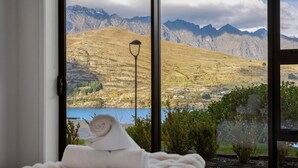 A room with a large window offering a view of a mountainous landscape and a lake.