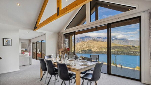 A dining area with a table set for six, large windows offering a mountain view, and a modern interior design.