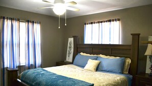 A bedroom with a bed, a nightstand, a ceiling fan, and curtains. - High Springs Hideaway – 4BR w/ Pool & Bar • Near Springs & UF • Walk to Town (High Springs)