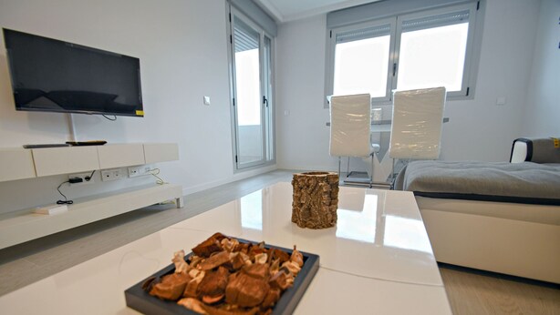A modern living room with a flat-screen TV, a coffee table with a decorative centerpiece, a sofa, and a large window providing natural light. - Timeless Elegance in Rivas (Rivas-Vaciamadrid)