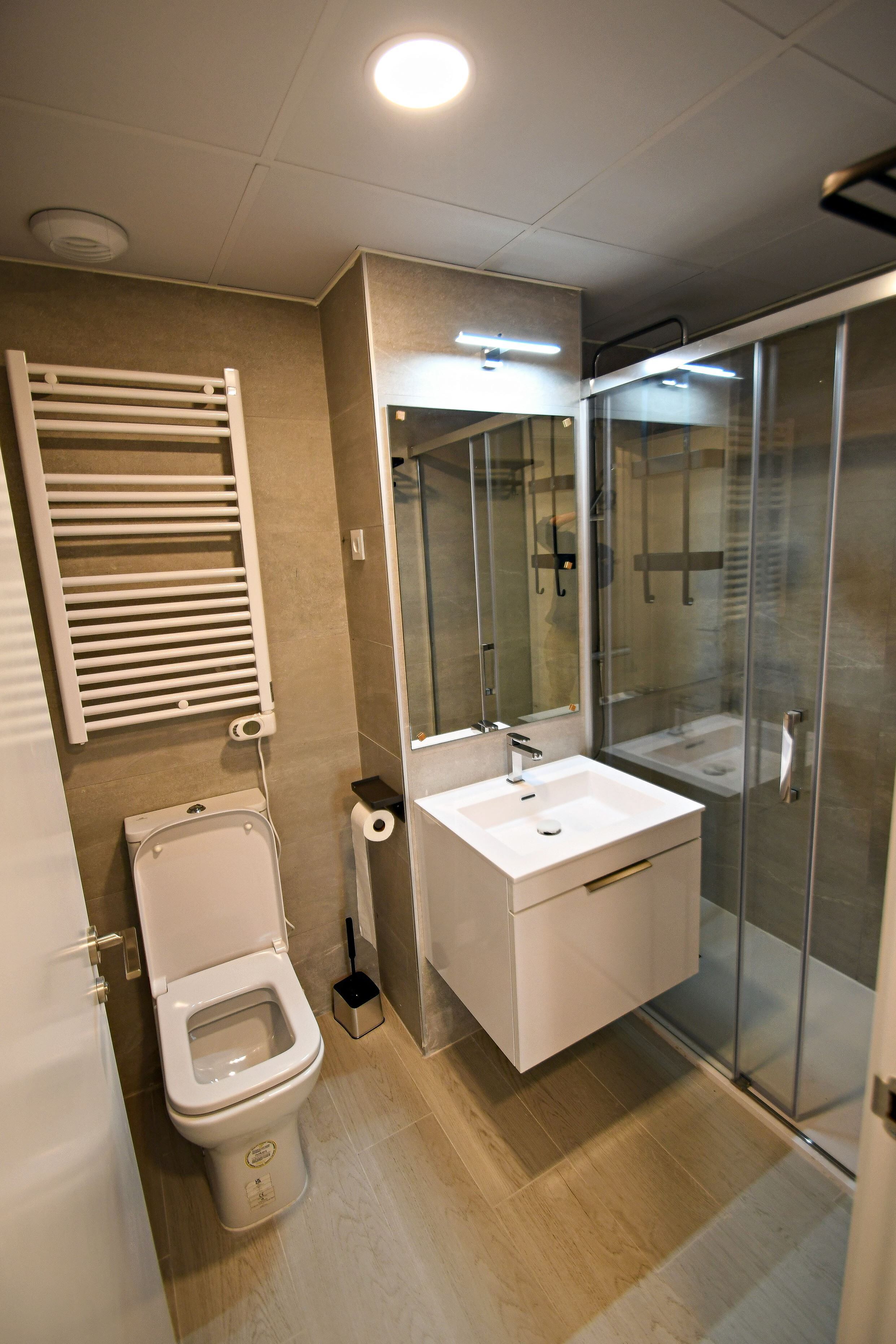 A modern bathroom with a toilet, sink, and glass shower enclosure.