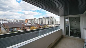A balcony with a view of residential buildings, a glass door, and a table with chairs. - Timeless Elegance in Rivas (Rivas-Vaciamadrid)