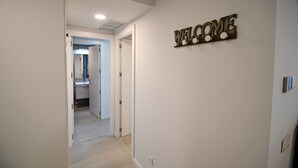 A hallway with a 'WELCOME' sign on the wall, leading to a bathroom with a sink and mirror. - Timeless Elegance in Rivas (Rivas-Vaciamadrid)
