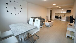 A modern living room with a dining area, a gray sofa, a white coffee table, and a large wall clock. - Timeless Elegance in Rivas (Rivas-Vaciamadrid)