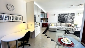 A modern apartment with a white desk, a sofa, and a dining table with a red centerpiece. - Sydney CBD 2Bedroom Apartment (Sydney)
