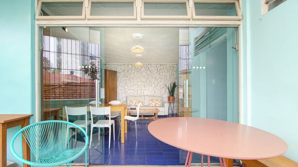 Un comedor con una mesa rosa, sillas color turquesa y un sofá blanco.