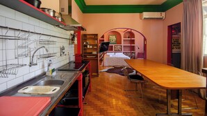 Una cocina compacta con una mesa de comedor de madera, horno empotrado y encimera roja.