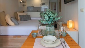 A cozy room with a bed, a dining table set with plates, glasses, and a vase of flowers. - WELCS ESTUDIO 237 PDA junto al mar (Platja d´Aro)