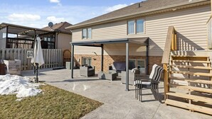 Un patio couvert avec des meubles d’extérieur, un barbecue et une terrasse en bois.
