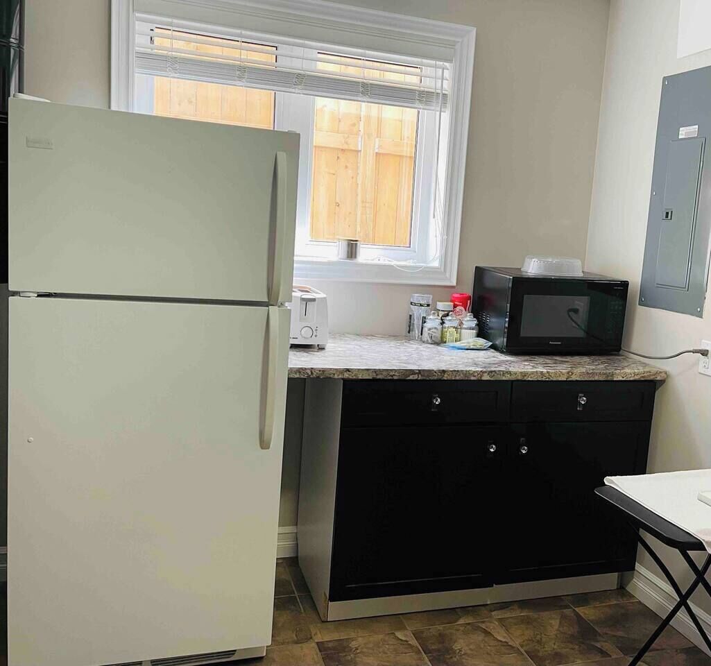 A compact kitchen with a refrigerator, microwave, and toaster.