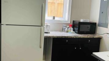 A compact kitchen with a refrigerator, microwave, and toaster.