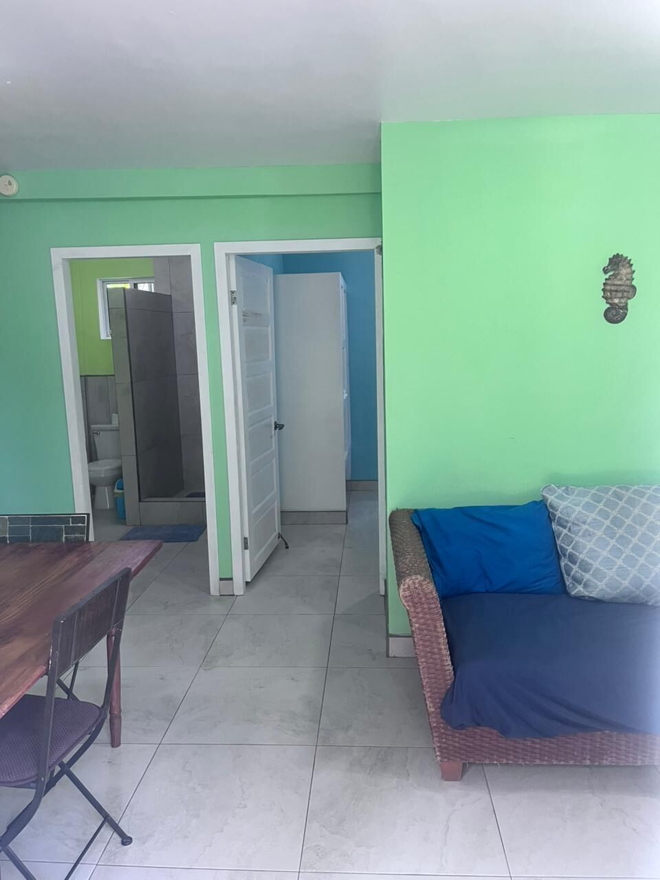 A room with a dining table, a sofa, and a door leading to a bathroom.