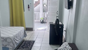 Et soveværelse med seng, sofa, fjernsyn og en dør der fører ud til en balkon.