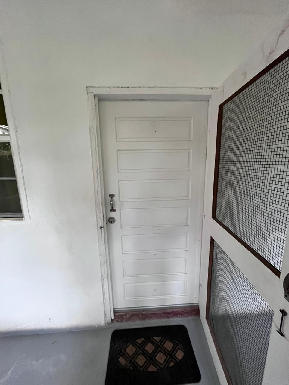 A white door with a metal security screen on the right side.