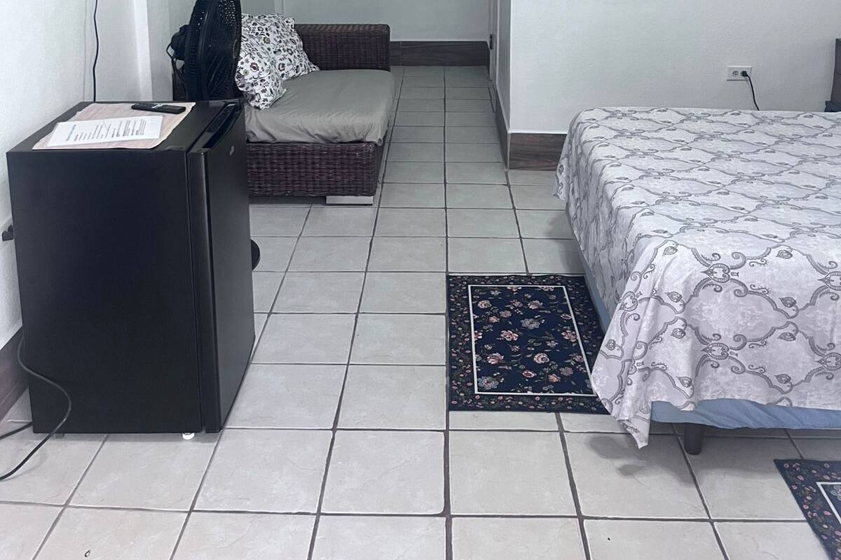 Un dormitorio con cama, escritorio, televisor y ventilador de pared.