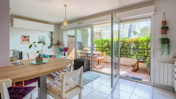 Une cuisine moderne avec une table en bois, des chaises blanches et un coin repas offrant une vue sur le jardin.