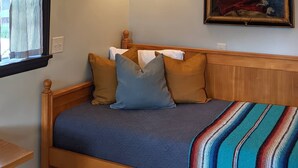 A bedroom with a wooden bed, a chandelier, a wall-mounted lamp, and a painting. - Crib house studio cabin - mountain views, .25mls to lake, quiet comfort! (Twin Lakes)
