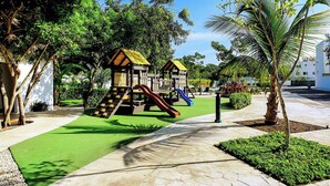 Un'area giochi con scivoli e strutture per arrampicarsi, immersa nel verde e con una passeggiata lastricata.