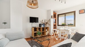 A modern living room with a sofa, a glass coffee table, a TV, and a bookshelf. - Holiday Home 'Casa Centro' with Sea View, Wi-Fi and Air Conditioning (Mijas)