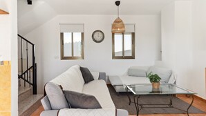 A modern living room with a sofa, a glass coffee table, and a hanging light fixture. - Holiday Home 'Casa Centro' with Sea View, Wi-Fi and Air Conditioning (Mijas)