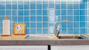 A kitchen with blue tiles, a stainless steel sink, and a paper towel holder.