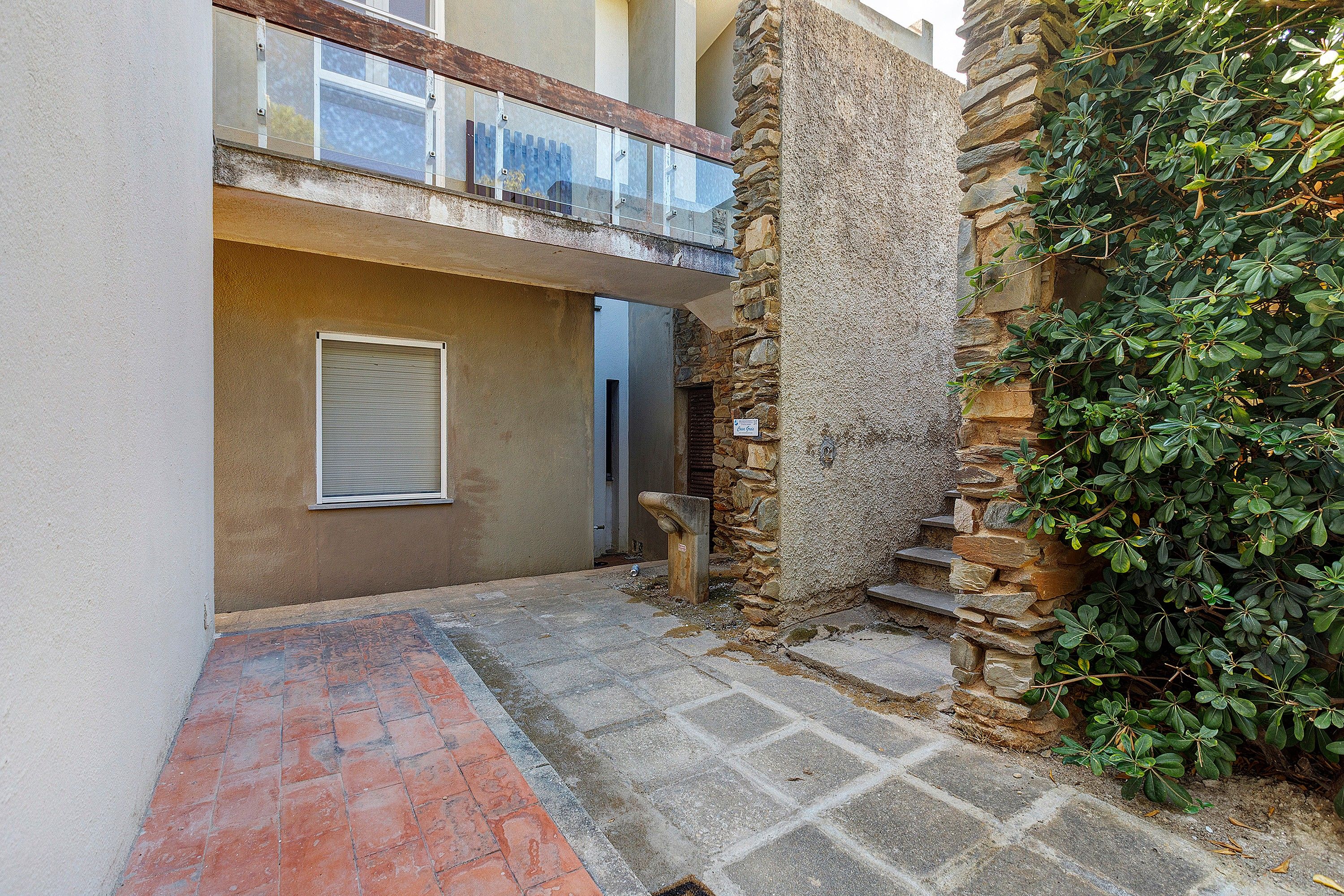 Un estrecho callejón con un muro de piedra en un lado y la entrada de un edificio con puerta de cristal.