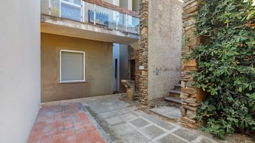 Un estrecho callejón con un muro de piedra en un lado y la entrada de un edificio con puerta de cristal.