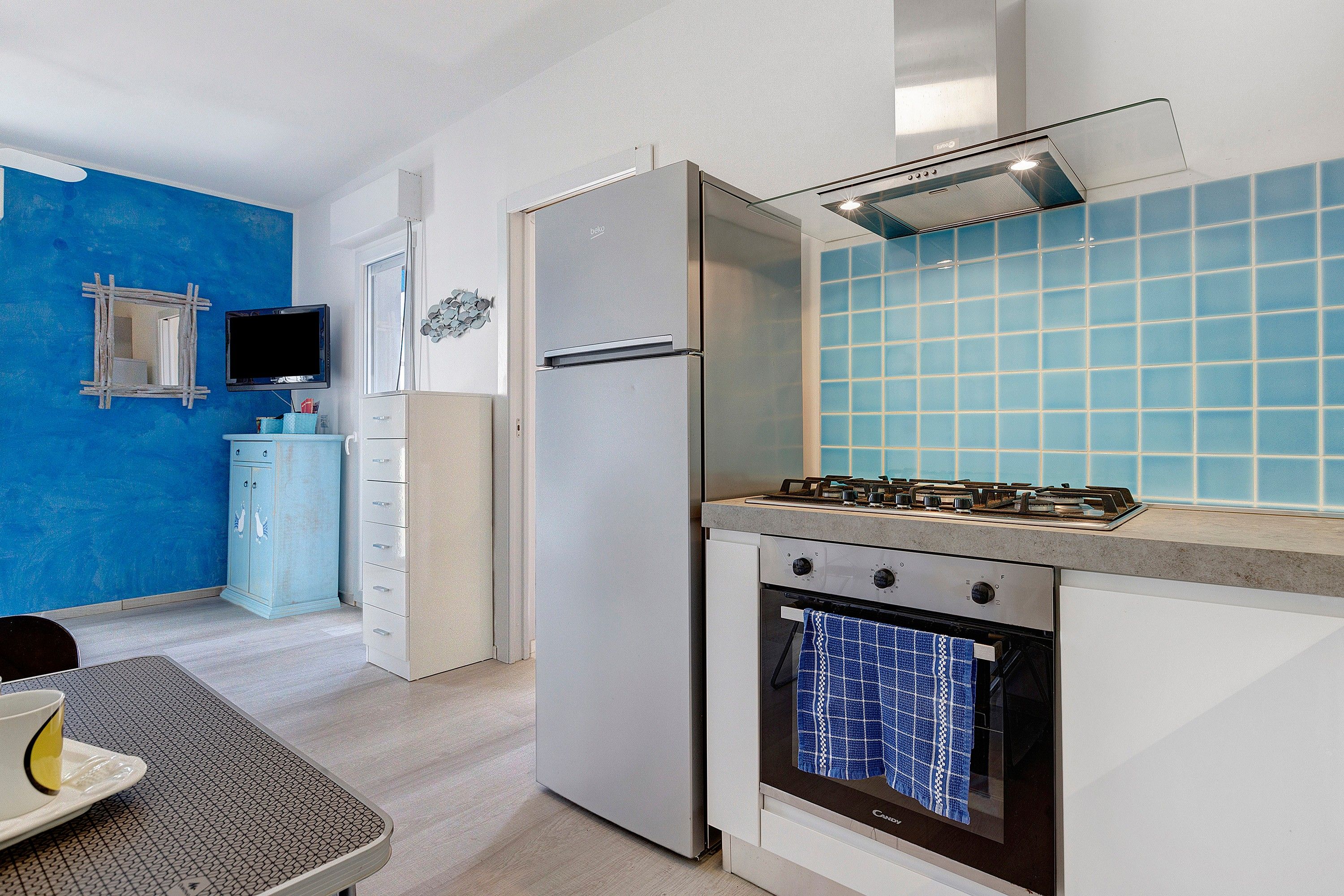 Cocina compacta con estufa, horno y un salpicadero de azulejos azules.