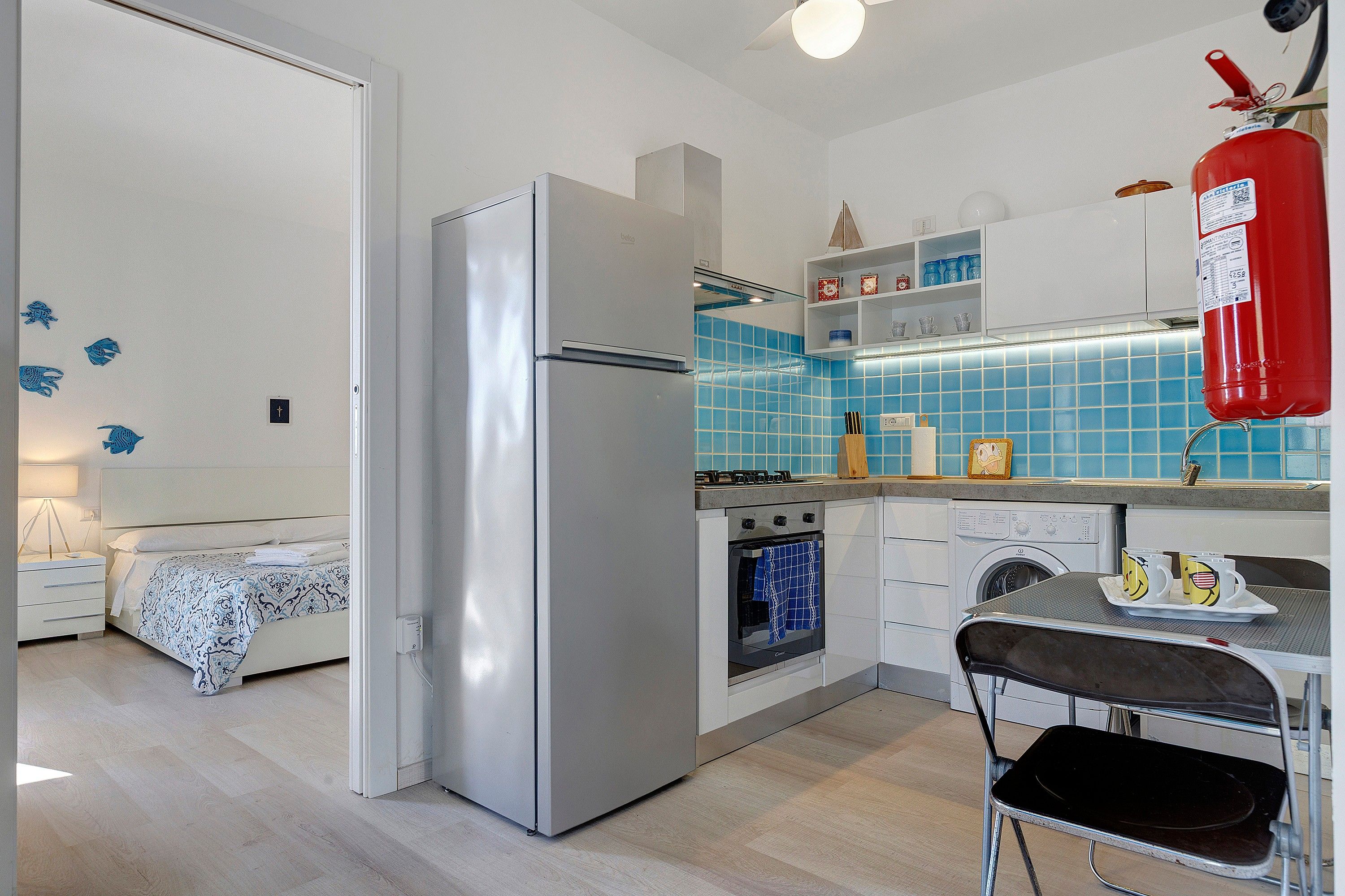 A compact kitchen with a refrigerator, oven, and washing machine.