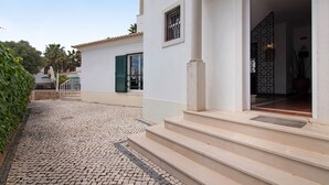A building with a cobblestone pathway leading to a set of steps and a door.