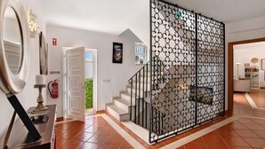 A staircase with a decorative metal railing, a white door leading outside, and a tiled floor.