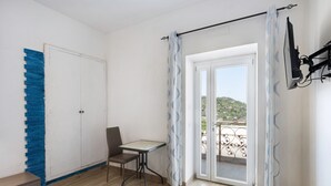 Ein Zimmer mit Schiebeglastür, einem Tisch, einem Stuhl und einem Kleiderschrank.
