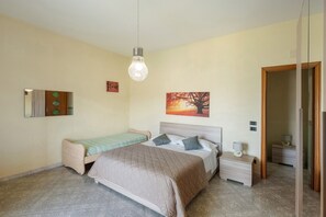 A bedroom with a bed, a bedside table, a nightstand, a mirror, and a wall-mounted picture.