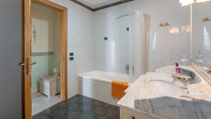 A bathroom with a bathtub, a shower, a sink, and a mirror. - Room 'Tripla Con Vista Montagna' with Mountain View, Shared Garden and Wi-Fi (Pimonte)
