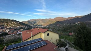 A residential area with a yellow building, solar panels, and a mountainous backdrop. - Room 'Tripla Con Vista Montagna' with Mountain View, Shared Garden and Wi-Fi (Pimonte)