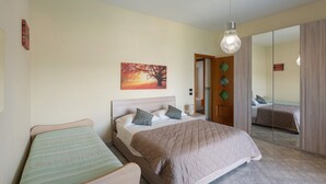 A bedroom with a bed, a smaller bed, a nightstand, a mirror, and a wall-mounted picture. - Room 'Tripla Con Vista Montagna' with Mountain View, Shared Garden and Wi-Fi (Pimonte)
