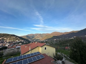 Un quartier résidentiel avec un bâtiment jaune, des panneaux solaires et une chaîne de montagnes en arrière-plan.