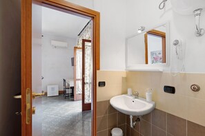 Une salle de bain avec un lavabo blanc, un miroir et un sèche-cheveux.