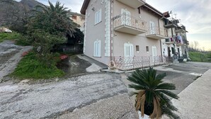 Ein mehrstöckiges Gebäude mit Balkonen, einem Gartenbereich mit Pflanzen und einem gepflasterten Weg.