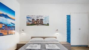 Un dormitorio con una cama, dos luces en la pared, un cuadro de un castillo y un armario.